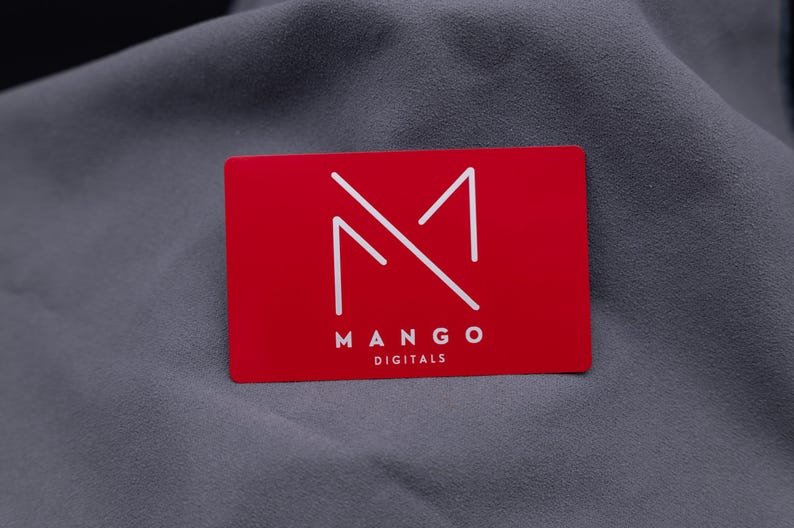 Businesskarte aus rotem Aluminium mit Mango-Digitals-Logo. Die gravierte Metallkarte überzeugt durch ihre matte Oberfläche, edle Optik und langlebige Qualität. Ideal für Start-ups, Designer und Unternehmen, die ihre Marke auf moderne, kreative Weise präsentieren möchten.