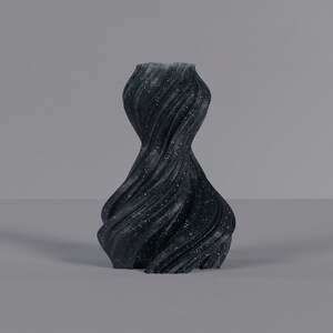 K&ouml;nnte beinhalten: Eine schwarze dekorative Vase mit einem wirbelnden, strukturierten Design. Die Vase hat ein gesprenkeltes Muster aus wei&szlig;en Punkten. Die Vase hat eine einzigartige, organische Form. Geeignet f&uuml;r die Inneneinrichtung.