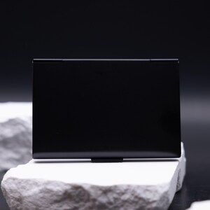 Schlichte Rückseite eines schwarzen Metall-Visitenkartenetuis ohne Gravur. Das minimalistische, leichte Design überzeugt durch Eleganz und Robustheit. Ideal für Männer und Frauen im Business-Bereich, die Karten sicher aufbewahren wollen. Es schützt zuverlässig vor Knicken und passt perfekt in jede Tasche. Ein modernes Accessoire für Meetings, Büro und Business-Events.