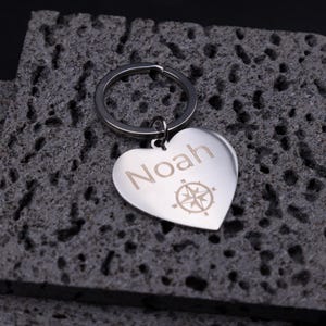 Personalisierter Schlüsselanhänger aus Edelstahl in Herzform, graviert mit dem Namen „Noah“ und Kompasssymbol. Die glänzende Oberfläche und das schlichte Design machen den Anhänger zu einem eleganten Accessoire am Schlüsselbund. Er symbolisiert Orientierung und Liebe – perfekt als individuelles Geschenk zum Valentinstag, Geburtstag oder Jubiläum.
