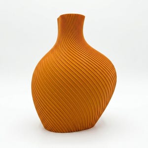 Puede incluir: Un jarr&oacute;n naranja con un dise&ntilde;o texturizado &uacute;nico. El jarr&oacute;n tiene una base ancha y redondeada que se estrecha hacia un cuello estrecho. La superficie est&aacute; cubierta de l&iacute;neas diagonales y acanaladas, creando un efecto de espiral. El jarr&oacute;n mide unos 25 cm de alto.