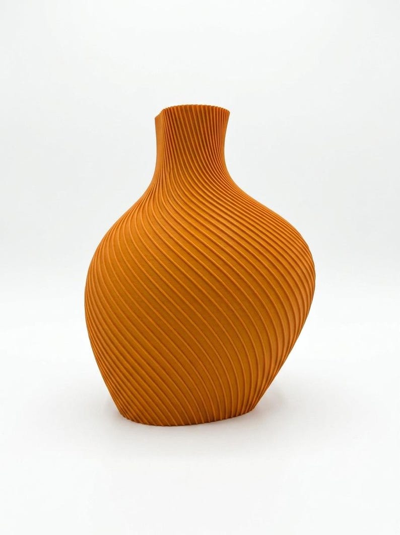 Puede incluir: Un jarr&oacute;n naranja con un dise&ntilde;o texturizado &uacute;nico. El jarr&oacute;n tiene una base ancha y redondeada que se estrecha hacia un cuello estrecho. La superficie est&aacute; cubierta de l&iacute;neas diagonales y acanaladas, creando un efecto de espiral. El jarr&oacute;n mide unos 25 cm de alto.