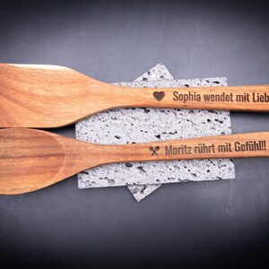 Flach gelegtes 2er-Set gravierter Kochlöffel aus Akazienholz mit Personalisierung. Gravuren „Sophia wendet mit Liebe!“ und „Moritz rührt mit Gefühl!!!“ mit Symbolen und Herzloch im Griff. Perfektes Geschenk für Kochfans, Paare oder Familien – nachhaltig, stilvoll und mit individueller Gravur.
