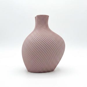 Puede incluir: Un jarr&oacute;n de color malva con un dise&ntilde;o texturizado &uacute;nico. El jarr&oacute;n tiene un cuerpo bulboso y un cuello delgado. La superficie presenta una serie de l&iacute;neas diagonales y estriadas que envuelven el jarr&oacute;n, creando un efecto de espiral. El jarr&oacute;n est&aacute; sobre un fondo blanco.