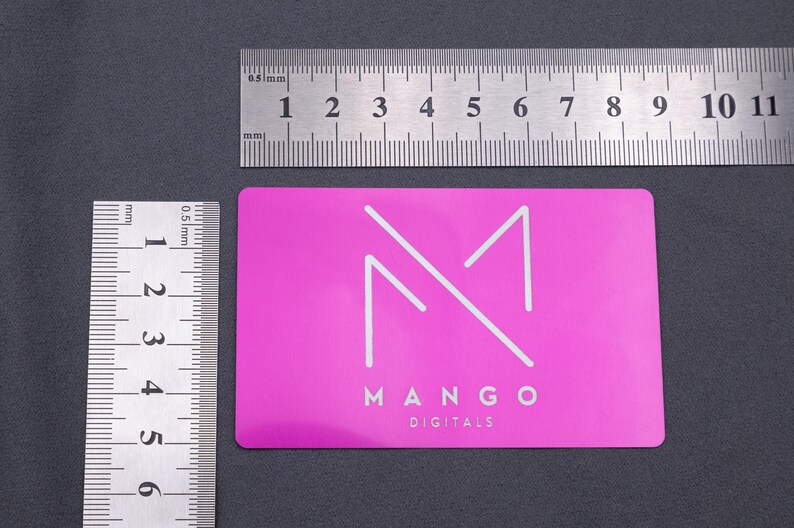 Aluminium-Visitenkarte in Metallic-Lila mit Mango Digital Logo, dargestellt neben einem Lineal zur Größenansicht. Standardgröße 85 x 54 mm, perfekt passend für Geldbeutel oder Visitenkartenetui. Die stabile Metalloberfläche ist kratzfest und langlebig, während das elegante Design für einen exklusiven Eindruck sorgt. Diese Karte vereint hochwertige Optik mit praktischer Funktionalität im Alltag.