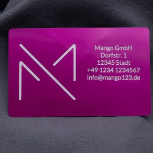 Lila Aluminium-Visitenkarte mit Mango GmbH Logo und detaillierten Geschäftsdaten: Adresse, Telefonnummer und E-Mail. Die lasergravierte Schrift hebt sich klar und dauerhaft von der metallischen Oberfläche ab. Diese hochwertige Geschäftskarte ist ideal für Networking, Kundenkontakte und Geschäftspartner. Dank der stabilen Aluminiumstruktur vermittelt sie Exklusivität und hebt sich deutlich von herkömmlichen Papierkarten ab.