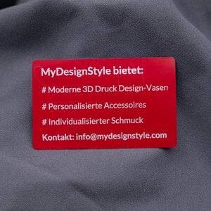 Rote Aluminiumkarte mit Gravur von Leistungen: moderne 3D-Druck-Designvasen, personalisierte Accessoires, individueller Schmuck. Darunter die Kontaktadresse von MyDesignStyle. Diese Metallkarte ist eine exklusive und langlebige Möglichkeit, das eigene Produktportfolio und die Marke stilvoll zu präsentieren.