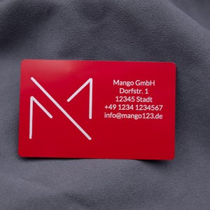 Visitenkarte aus rotem Aluminium mit Mango-Digitals-Logo und vollständigen Kontaktdaten. Die robuste Metallkarte im Kreditkartenformat ist eine exklusive und langlebige Alternative zu klassischen Papierkarten. Perfekt für Business, Networking und professionelle Präsentationen.