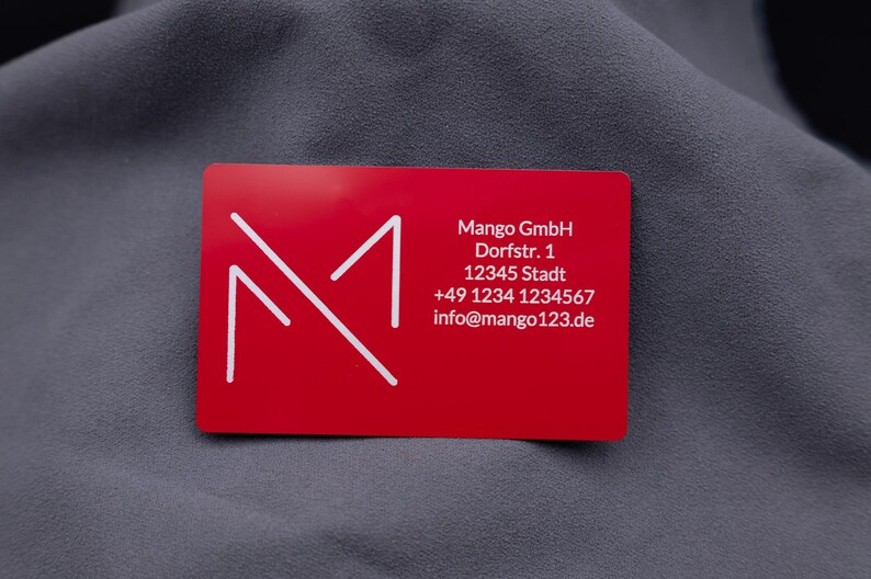 Visitenkarte aus rotem Aluminium mit Mango-Digitals-Logo und vollständigen Kontaktdaten. Die robuste Metallkarte im Kreditkartenformat ist eine exklusive und langlebige Alternative zu klassischen Papierkarten. Perfekt für Business, Networking und professionelle Präsentationen.