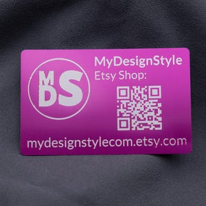 Aluminium-Visitenkarte in Lila mit MyDesignStyle-Logo, Etsy-Shop QR-Code und Webadresse. Das Design ist klar und modern, perfekt für Markenaufbau und Kundenkommunikation. Durch die stabile Metalloberfläche hebt sich diese Karte von klassischen Papierkarten ab und wirkt besonders hochwertig. Mit dem QR-Code können Kunden direkt den Shop aufrufen – eine moderne und funktionale Businesskarte.