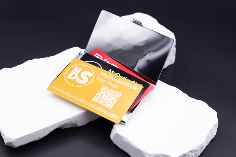 Größenvergleich von Leichtes Visitenkartenetui Metall silber aus Metall. Diese Aufnahme passt zum Suchwort Kartenetui geschenk aus dem MyDesignStyle Sortiment. Praktisch und stilvoll als Personalisiertes etui im Alltag. Weitere Motive zum Thema Visitenkarten halter bei MyDesignStyle entdecken.