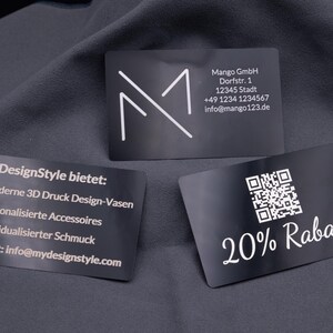 Drei exklusive Visitenkarten aus schwarzem Aluminium mit Lasergravur. Links gravierte Infos zu angebotenen Produkten, in der Mitte eine Businesskarte mit Logo und Kontaktdaten, rechts eine Rabattkarte mit QR-Code und Gravur „20% Rabatt“. Die hochwertigen Metallkarten sind stabil, elegant und modern – ideal als personalisierte Businesskarten, Werbekarten oder Kundenkarten.