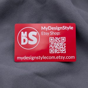 Visitenkarte aus rotem Aluminium mit eingraviertem MDS-Logo, Etsy-Shop-Adresse und QR-Code. Die matte Metallkarte ist langlebig, robust und modern – perfekt für Branding, Marketing und kreative Businessideen. Eine edle Alternative zu klassischen Papierkarten, ideal für professionelle Unternehmenspräsentationen.