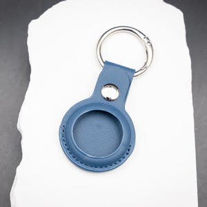 Rückseite eines blauen AirTag Schlüsselanhängers aus PU Leder ohne Gravur. Die runde Form ist exakt auf den Apple AirTag abgestimmt. Saubere Nähte und robuster Edelstahlring sorgen für Langlebigkeit. Praktisches Zubehör zur sicheren Befestigung von AirTags an Schlüsseln Rucksack oder Tasche.