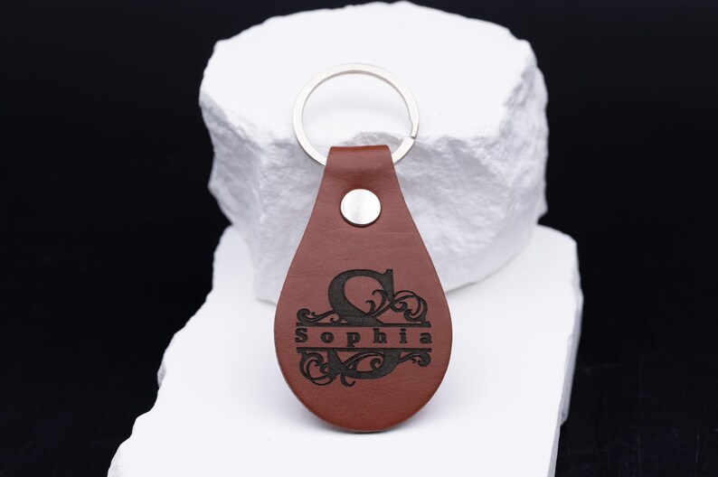 Personalisierter Schlüsselanhänger aus hochwertigem braunem Kunstleder mit individueller Lasergravur. Das elegante Monogramm mit Namen wie „Sophia“ verleiht dem Accessoire eine edle, persönliche Note. Durch den robusten Metallring eignet sich der Anhänger ideal für Auto-, Haus- oder Büroschlüssel. Perfekt als Geschenk für Männer, Frauen oder Paare, die stilvolle und langlebige Accessoires schätzen.