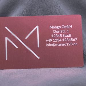 Visitenkarte aus roségoldenem Aluminium mit Gravur von Mango-Logo, Adresse, Telefonnummer und E-Mail. Die matte Oberfläche wirkt hochwertig, die Karte ist robust und langlebig. Perfekt für Unternehmer, die eine moderne, exklusive Businesskarte für Networking und professionelle Präsentationen nutzen möchten.