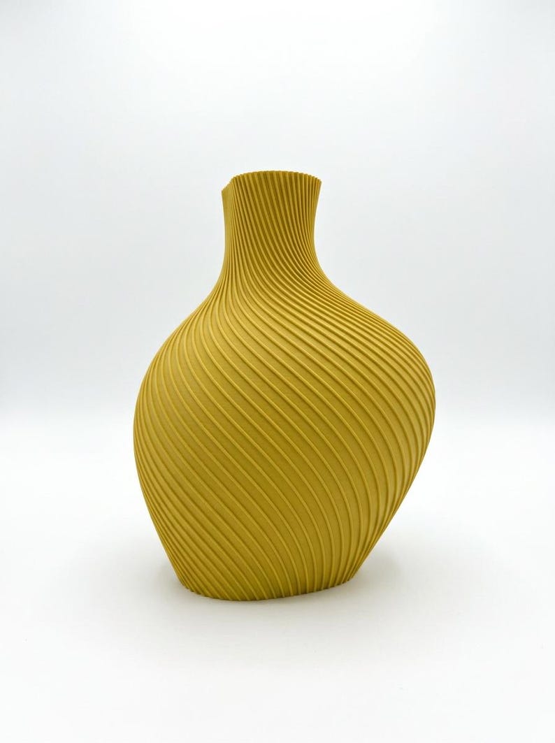 Puede incluir: Jarr&oacute;n amarillo mostaza con un dise&ntilde;o espiral texturizado &uacute;nico. El jarr&oacute;n tiene una base ancha que se estrecha hacia un cuello estrecho. El jarr&oacute;n mide aproximadamente 25 cm de alto y es un adorno decorativo.