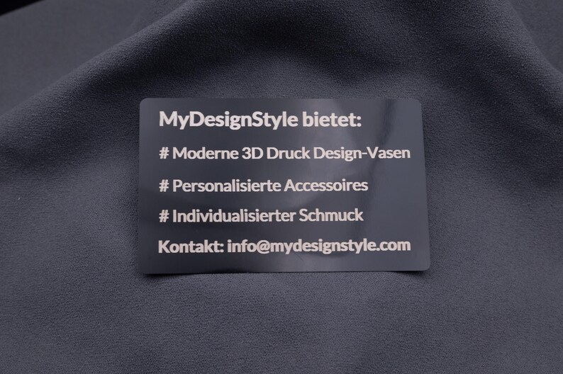 Exklusive schwarze Metallkarte mit Gravur der angebotenen Produkte von MyDesignStyle: moderne 3D-Druck-Vasen, personalisierte Accessoires, individueller Schmuck. Ergänzt mit Kontakt-E-Mail. Robuste Alternative zu Papierkarten, ideal für Business, Marketing und Kundengewinnung.