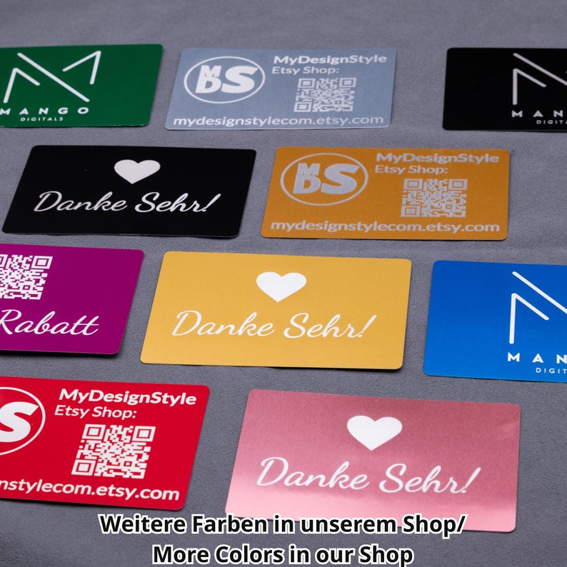 Mehrere Aluminium-Visitenkarten in verschiedenen Farben, darunter Roségold, Schwarz, Silber, Gold, Blau, Rot und Grün. Gravuren zeigen Firmenlogos, QR-Codes, Dankeschön-Motive und Rabattaktionen. Die Metallkarten sind langlebig, robust und stilvoll – ideal als Businesskarten, Dankeskarten oder Werbemittel. Hinweis: weitere Farbvarianten im Shop erhältlich.