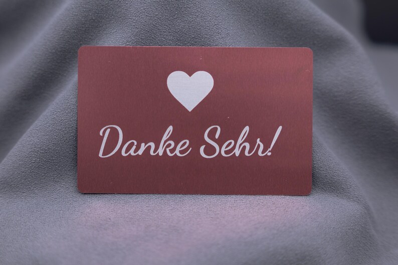 Dankeskarte aus roségoldenem Aluminium mit Herzsymbol und Gravur „Danke Sehr!“. Die matte Metalloberfläche wirkt stilvoll und elegant, die Karte ist langlebig und robust. Perfekt als exklusive Dankeskarte für Kunden, Partner oder besondere Anlässe – eine moderne Alternative zu Papierkarten im Premium-Look.