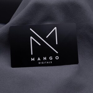Elegante Businesskarte aus Aluminium in Schwarz mit graviertem Mango-Digitals-Logo. Die matte Metallkarte überzeugt durch modernes Design und langlebige Qualität – ideal für Designer, Start-ups und Unternehmen, die Wert auf einen exklusiven Markenauftritt legen.