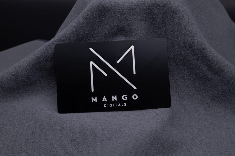 Elegante Businesskarte aus Aluminium in Schwarz mit graviertem Mango-Digitals-Logo. Die matte Metallkarte überzeugt durch modernes Design und langlebige Qualität – ideal für Designer, Start-ups und Unternehmen, die Wert auf einen exklusiven Markenauftritt legen.