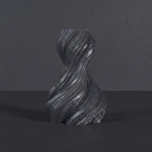 K&ouml;nnte beinhalten: Eine dunkelgraue, wirbelnde Vase mit einer strukturierten, glitzernden Oberfl&auml;che. Die Vase hat ein einzigartiges, gedrehtes Design und steht auf einer dunklen Oberfl&auml;che. Die Gesamt&auml;sthetik ist modern und k&uuml;nstlerisch.