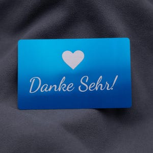 Dankeskarte aus Aluminium in elegantem Blau mit Herzsymbol und Gravur „Danke Sehr!“. Die klare Gestaltung mit matter Oberfläche und abgerundeten Ecken vermittelt Wertschätzung und Eleganz. Ideal geeignet für Unternehmen, Online-Shops oder Designer, die ihren Kunden eine persönliche Botschaft in exklusiver, langlebiger Form überreichen möchten – weit mehr als eine einfache Papierkarte.