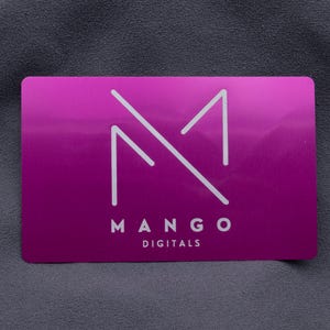 Edle lila Visitenkarte aus Aluminium mit minimalistischem Mango Digital-Logo in präziser Gravur. Das klare, reduzierte Design betont die Eleganz der metallic glänzenden Oberfläche. Diese Businesskarte eignet sich perfekt für kreative Agenturen, Unternehmen oder Selbstständige, die einen modernen und professionellen Eindruck hinterlassen wollen. Die robuste Aluminiumstruktur sorgt für Langlebigkeit und Wertigkeit.