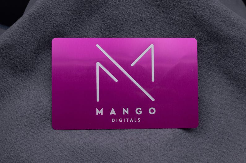 Edle lila Visitenkarte aus Aluminium mit minimalistischem Mango Digital-Logo in präziser Gravur. Das klare, reduzierte Design betont die Eleganz der metallic glänzenden Oberfläche. Diese Businesskarte eignet sich perfekt für kreative Agenturen, Unternehmen oder Selbstständige, die einen modernen und professionellen Eindruck hinterlassen wollen. Die robuste Aluminiumstruktur sorgt für Langlebigkeit und Wertigkeit.
