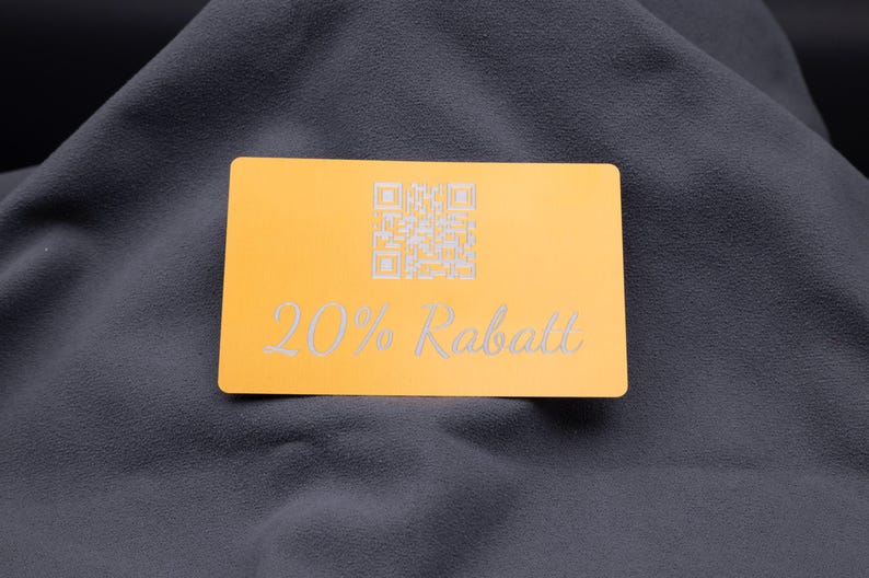 Exklusive Rabattkarte aus Aluminium in Hellgold mit Gravur „20% Rabatt“ und integriertem QR-Code. Mit abgerundeten Kanten, matter Oberfläche und edler Gravur eignet sich die Karte hervorragend als langlebiges Marketingtool für Shops, Events und Kundenaktionen. Ein stilvolles Werbemittel, das mit seinem eleganten Metall-Design Professionalität und Qualität unterstreicht.