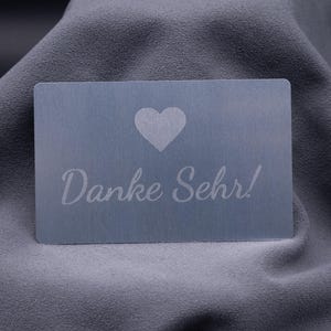 Exklusive Dankeskarte aus Aluminium in Silber mit graviertem Herzsymbol und dem Schriftzug „Danke Sehr!“. Die matte Metalloberfläche wirkt modern und hochwertig, eine stilvolle Möglichkeit, Kunden oder Geschäftspartnern Wertschätzung auszudrücken. Langlebig, robust und elegant – diese Karte ist eine außergewöhnliche Alternative zu klassischen Papierkarten und ideal für Unternehmen mit Premium-Anspruch.