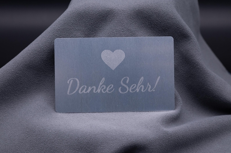 Exklusive Dankeskarte aus Aluminium in Silber mit graviertem Herzsymbol und dem Schriftzug „Danke Sehr!“. Die matte Metalloberfläche wirkt modern und hochwertig, eine stilvolle Möglichkeit, Kunden oder Geschäftspartnern Wertschätzung auszudrücken. Langlebig, robust und elegant – diese Karte ist eine außergewöhnliche Alternative zu klassischen Papierkarten und ideal für Unternehmen mit Premium-Anspruch.