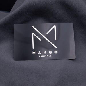 Einzelne schwarze Aluminium-Visitenkarte mit weißem Mango-Digitals-Logo, minimalistisch und edel graviert. Die matte Oberfläche verstärkt den modernen Look. Langlebig, stabil und auffällig – ideal für Unternehmer, Start-ups und Designer, die ihre Marke auf stilvolle Weise präsentieren wollen.