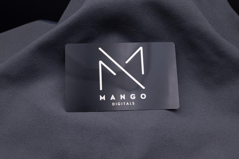 Einzelne schwarze Aluminium-Visitenkarte mit weißem Mango-Digitals-Logo, minimalistisch und edel graviert. Die matte Oberfläche verstärkt den modernen Look. Langlebig, stabil und auffällig – ideal für Unternehmer, Start-ups und Designer, die ihre Marke auf stilvolle Weise präsentieren wollen.