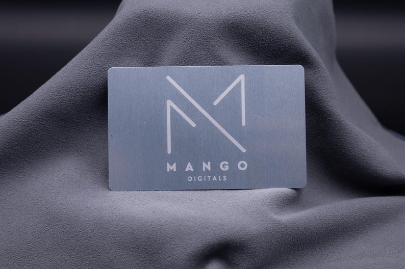 Visitenkarte aus Metall in Silber mit modernem Logo „Mango Digitals“. Die Aluminiumkarte überzeugt durch ihre matte Oberfläche, exklusive Haptik und langlebige Qualität. Eine stilvolle Alternative zur klassischen Papier-Visitenkarte, ideal für Unternehmer, Designer und Start-ups, die ihre Marke professionell und kreativ präsentieren möchten. Perfekt für Business-Events, Networking und Kundenbindung.