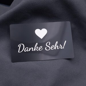 Schwarze Dankeskarte aus Aluminium mit Herzsymbol und Gravur „Danke Sehr!“. Die matte Oberfläche der Metallkarte wirkt hochwertig und langlebig. Ideal als exklusive Dankeskarte für Kunden, Partner oder besondere Anlässe. Eine kreative Alternative zur klassischen Papierkarte.