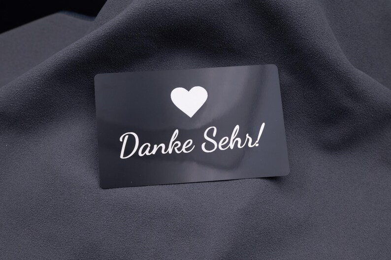 Schwarze Dankeskarte aus Aluminium mit Herzsymbol und Gravur „Danke Sehr!“. Die matte Oberfläche der Metallkarte wirkt hochwertig und langlebig. Ideal als exklusive Dankeskarte für Kunden, Partner oder besondere Anlässe. Eine kreative Alternative zur klassischen Papierkarte.