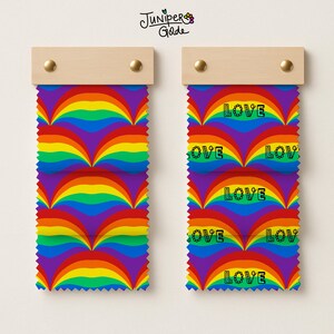 May include: Two fabric swatches with a rainbow pattern and the word "LOVE" printed on them. The swatches are attached to wooden boards with gold-colored tacks. The Juniper & Golde logo is in the top left corner.