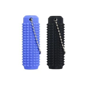 Op de afbeelding: Twee getextureerde, cilindrische objecten. Eén is helderblauw, de andere zwart. Beide hebben een noppenpatroon en een kleine ketting aan de bovenkant bevestigd. De objecten zijn waarschijnlijk sleutelhangers of vergelijkbare accessoires.