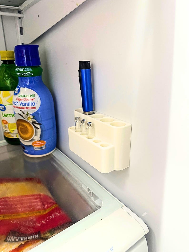 Insulin pen and peptide vial fridge organizer mounted inside refrigerator wall, GLP-1 storage holder keeping injection pens and cartridges visible, clean and discreet cold storage organization system