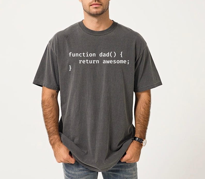 K&ouml;nnte beinhalten: Dunkelgraues T-Shirt mit dem wei&szlig;en Text "function dad() { return awesome; }". Das T-Shirt hat einen Rundhalsausschnitt und kurze &Auml;rmel. Der Stoff wirkt weich und abgenutzt. L&auml;ssiger Stil.