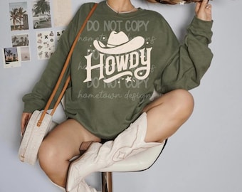 May include: Green sweatshirt with a white cowboy hat and the text "Howdy" in a vintage style font. The text also includes the phrase "Do Not Copy" and "Hometown Designs".