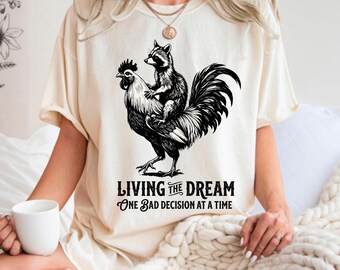 Living the Dream T-Shirt Design – Raccoon & Rooster Sarcastic Graphic (PNG SVG)