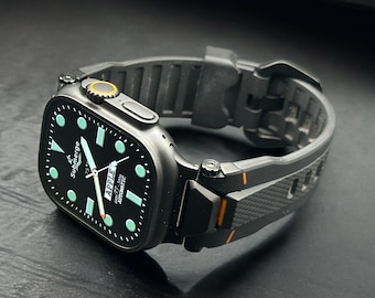 May include: A black Apple Watch with a black band. The watch face is black with light blue and white accents, and the text "Submerge" and "Apple" are visible. The band has orange accents.