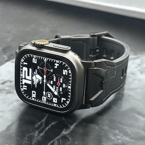 May include: A black smartwatch with a black band. The watch face displays the time with white numerals and hands against a black background. The watch has a textured band and a yellow accent on the side.