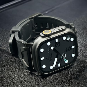 Puede incluir: Un reloj inteligente negro con una correa negra. La esfera del reloj muestra la hora, la fecha y la palabra "Submerge". El reloj tiene una pantalla digital con marcadores y agujas blancas. El reloj está sobre una superficie oscura.