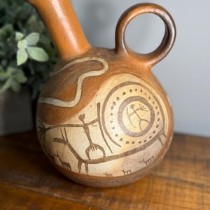 Könnte beinhalten: Eine weiße Keramik-Tasse mit schwarzem Henkel und dem Text "But First, Coffee" in schwarzer, fetter Schrift. Die Tasse steht auf einer weißen Oberfläche.