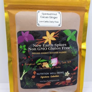 May include: A gold pouch with a brown powder inside. The pouch has a label that reads "Spirited Hot Cacao Ginger Low-Carbs Dairy Free" and "New Earth Spices Non GMO Gluten Free INFUSED ENERGY BOOSTER BLENDS Enhanced Enlight Inspired By Tesla 369 The Alchemy of Herbs NUTRITION WELL-BEING Signature Collection www.New EarthSpices.com".