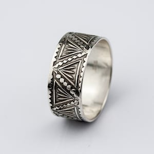 May include: A silver ring with a geometric pattern around the band.